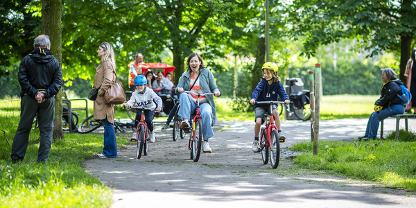 Een moeder met 2 kinderen rijden met de gekke fietsen door Distelhoek.
